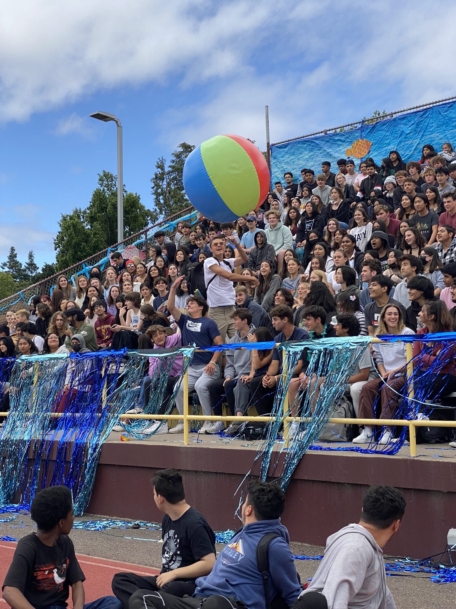 Students leap to toss the beach ball across the bleachers.