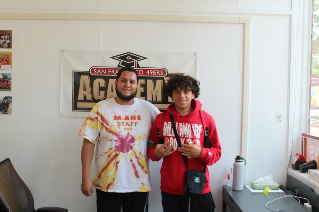 Armando Castillo (left) and Lazarus Thompson (right) stand in front of 49ers Academy sign