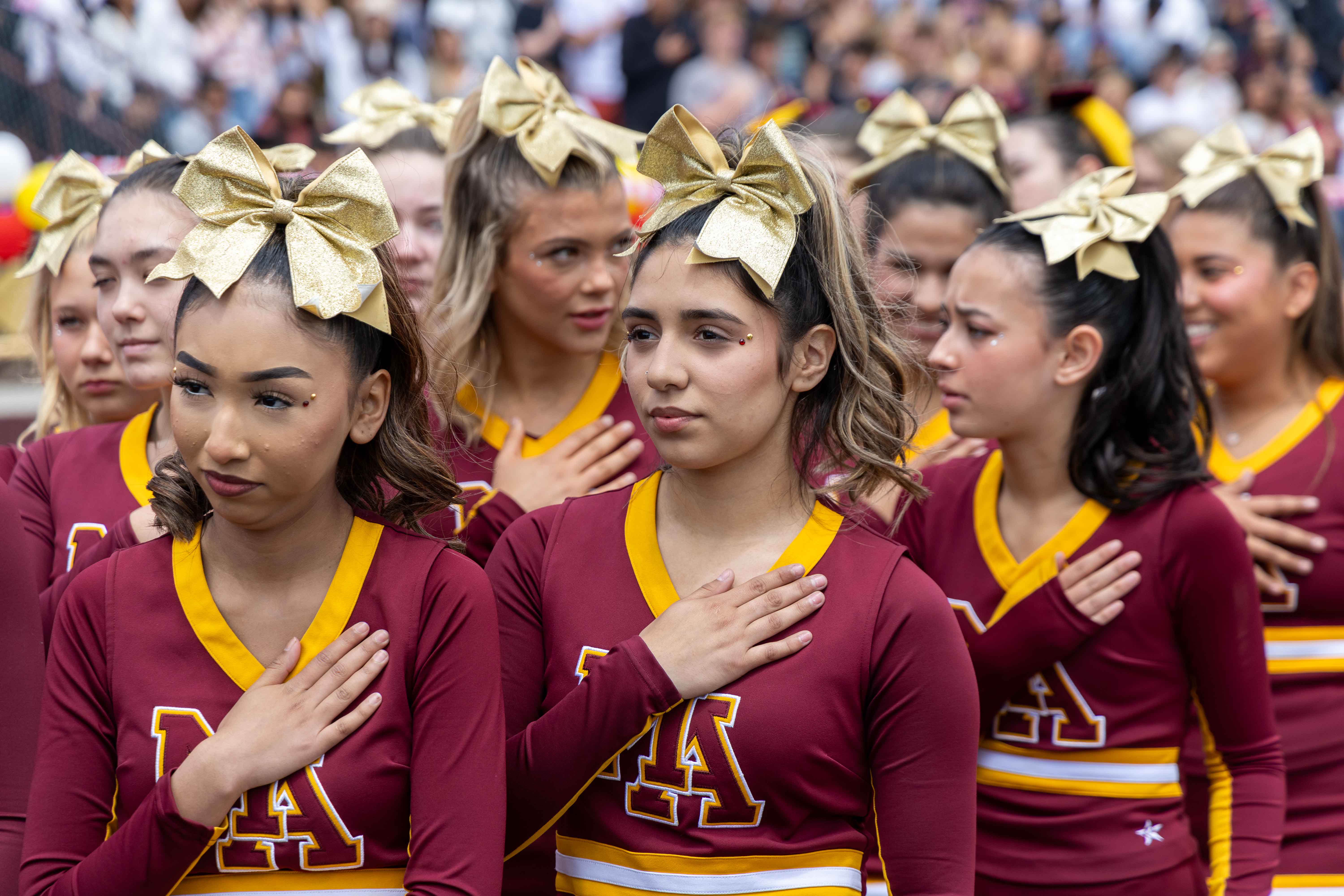 Cheerleaders stand to pledge for the national anthem.