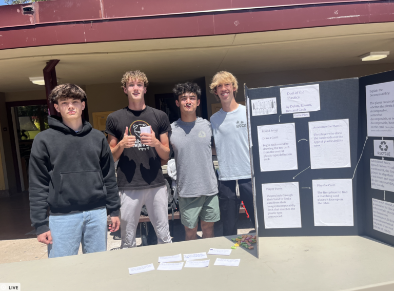 Kelly and classmates pose by their APES poster.